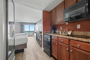 A modern kitchen with granite countertops, wooden cabinets, and a built-in microwave. - Oceanfront Two Queen Room + Lazy River & Hot Tub (Myrtle Beach)