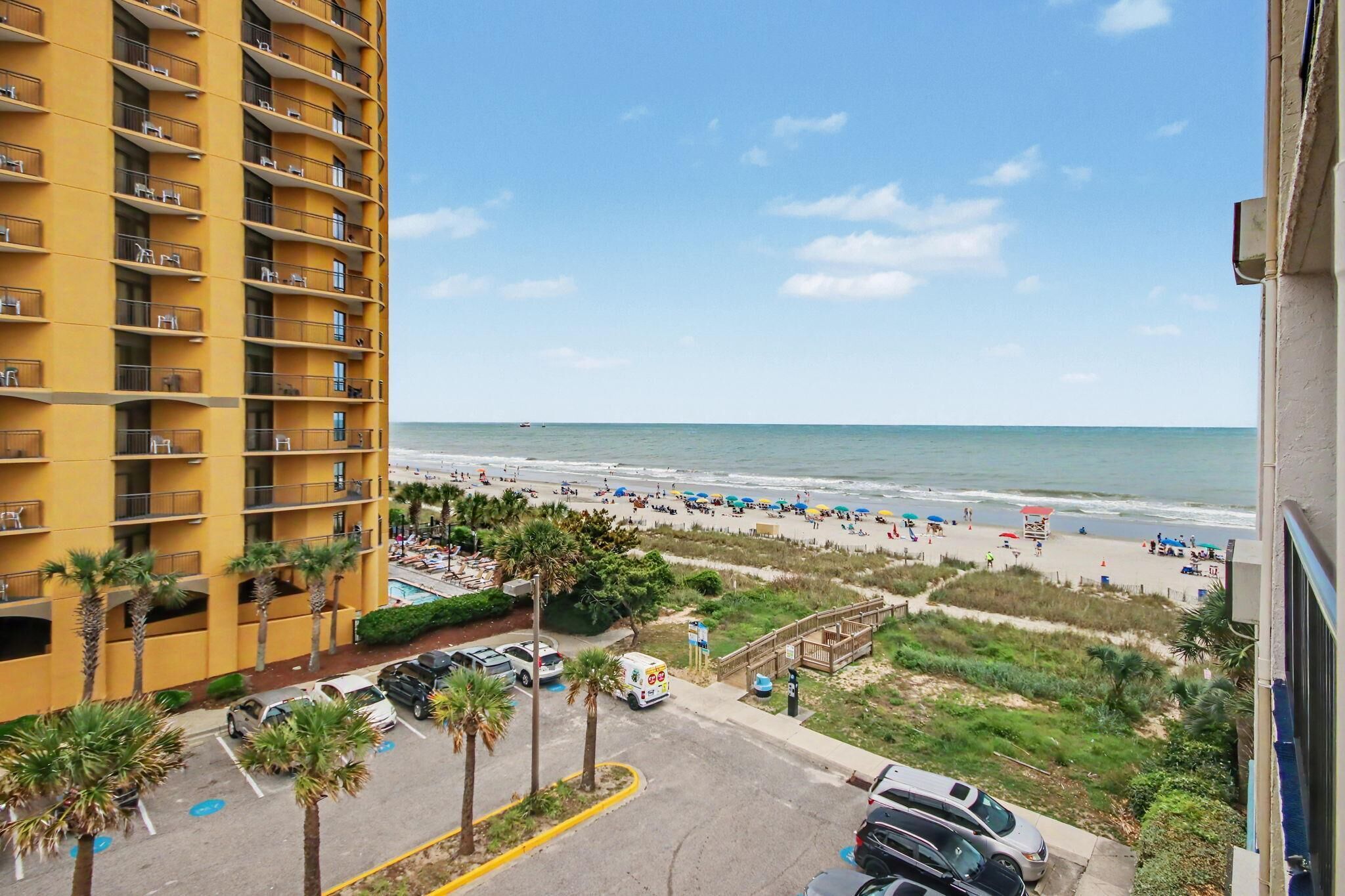 A high-rise hotel with balconies overlooking a beach.