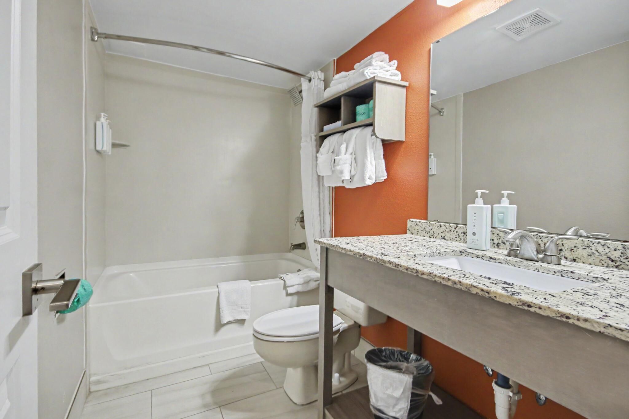 A bathroom with a bathtub, toilet, and a vanity with a sink and mirror.