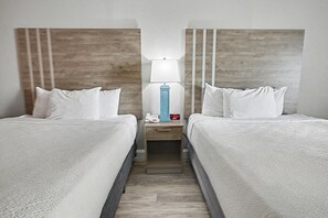 A hotel room with two beds, a nightstand with a lamp, a clock, and a phone. - Resort View Two Queen Standard Room + Lazy River & Hot Tub (Myrtle Beach)