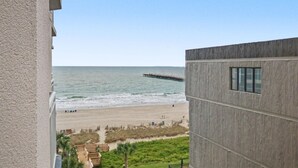 Une vue sur une plage, prise depuis un bâtiment dont la façade est en béton et qui possède une fenêtre.