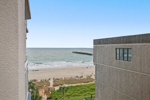 Blick auf einen Strand von einem Gebäude mit Betonfassade und einem Fenster.