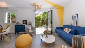 Ein modernes Wohnzimmer mit Sofa, Sessel, Couchtisch und einem Essbereich mit Stühlen und Tisch.