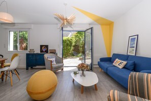 Een moderne woonkamer met een bank, fauteuil, salontafel en een eethoek met stoelen en een tafel.