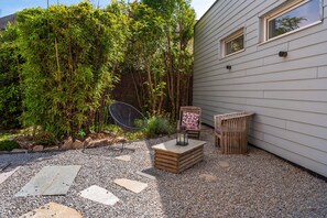 Een terras met een houten tafel, een stoel en een lantaarn.