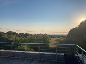 A balcony with a metal railing, a view of a landscape with trees and a clear sky. - Maison Hoali – Presqu’île de Rhuys: Sea View, Wi-Fi, and Air Conditioning (Saint-Armel)