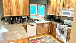 Una cocina con armarios de madera, una estufa blanca, un microondas y una ventana con vistas.