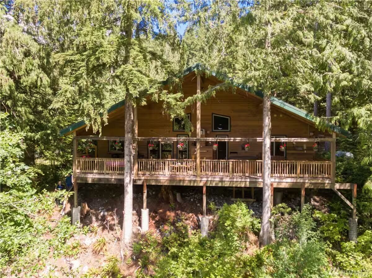 Une cabane en bois dotée d’un balcon, entourée d’une forêt dense.