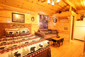 Ein rustikales Holzhaus-Interieur mit Bett, Sofa und Esstisch.