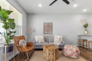 A modern living room with a sofa, a coffee table, a chair, and a large plant. - Cozy 1-bedroom in the heart of Madison (Madison)