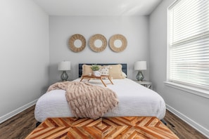 A bedroom with a bed, bedside tables, wall decor, and a window with blinds. - Cozy 1-bedroom in the heart of Madison (Madison)