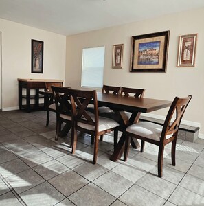 Un comedor con una mesa y sillas de madera, una mesita auxiliar y cuadros en las paredes.
