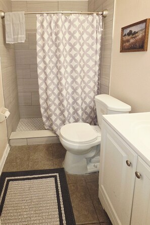 A bathroom with a shower, toilet, and cabinet.