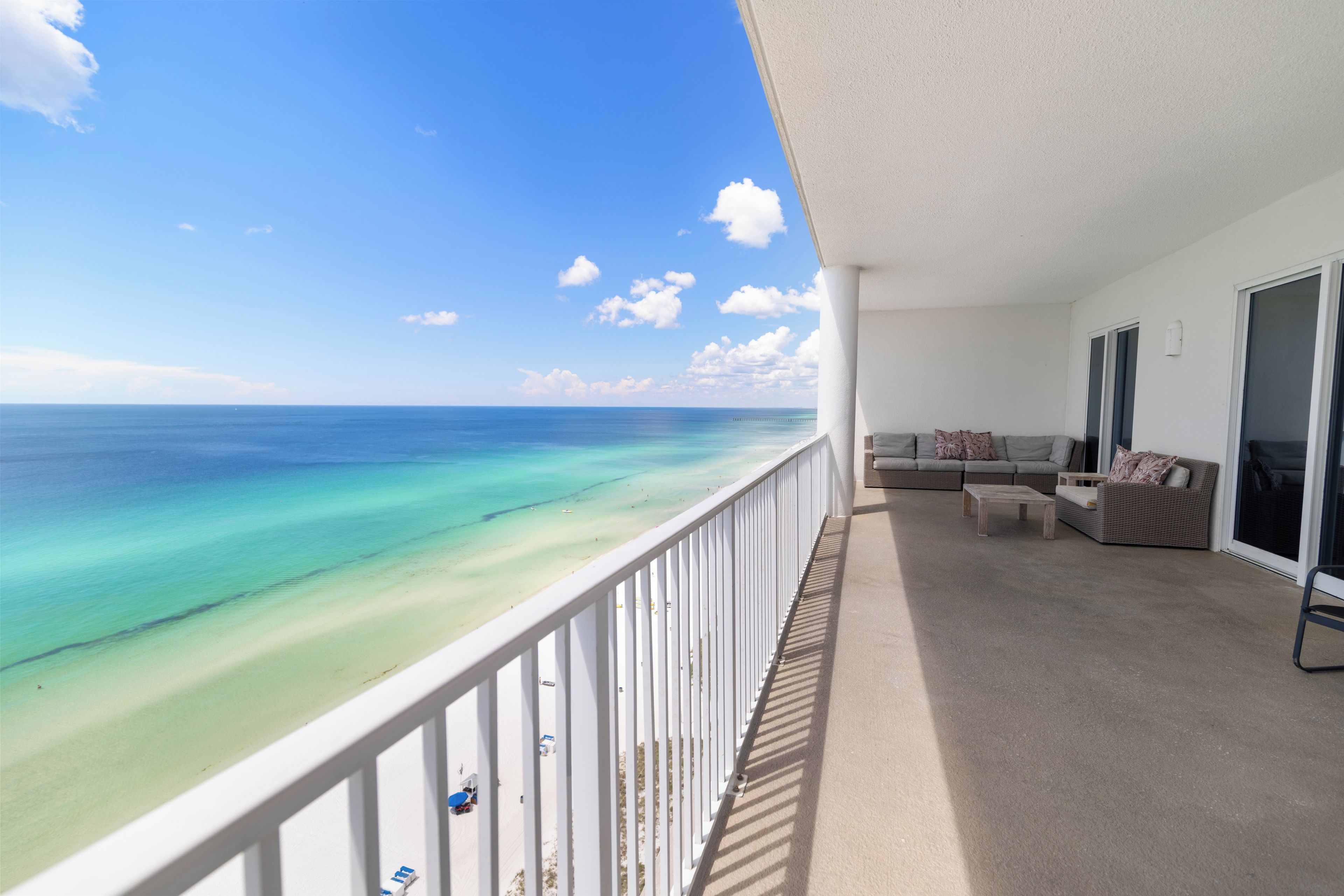 Ein Balkon mit Blick auf das Meer, eine Sitzecke mit Kissen und ein weißes Geländer.