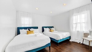 Ett hotellrum med två sängar, vitt sänglinne och ett trägolv.