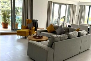 Ein modernes Wohnzimmer mit einer Couch, Sesseln und einem Couchtisch.