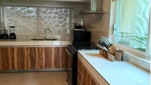 Ett modernt kök med en väggbeklädnad av marmor, träskåp, en inbyggd spis och ett fönster med utsikt.