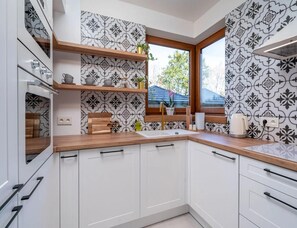 A modern kitchen with white cabinetry, wooden countertops, and patterned backsplash. - Comfortable Holiday Villa, Sauna, Jacuzzi (Brzeznica)