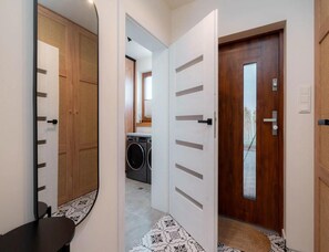 A hallway with a washing machine, a bench, and a door leading to another room. - Comfortable Holiday Villa, Sauna, Jacuzzi (Brzeznica)