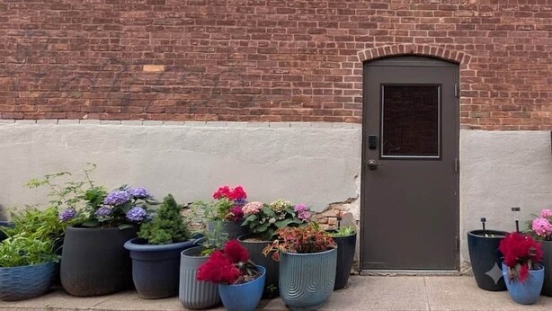 Un bâtiment en briques avec une porte et des plantes en pot devant.