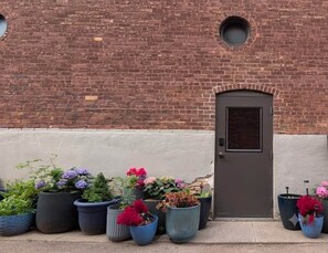 A brick building with a door and potted plants in front. - Historic Main St w/ Lake View | The Flatwater Loft (Ashland)