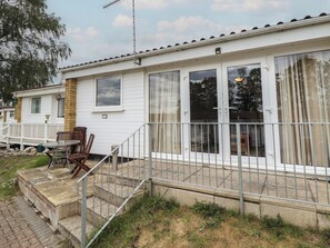 Ein Bungalow mit einer Terrasse, einem kleinen Tisch und Stühlen sowie Treppen zum Eingang.