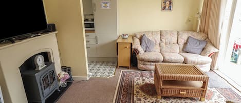 Una sala de estar con chimenea, sofá y televisor.