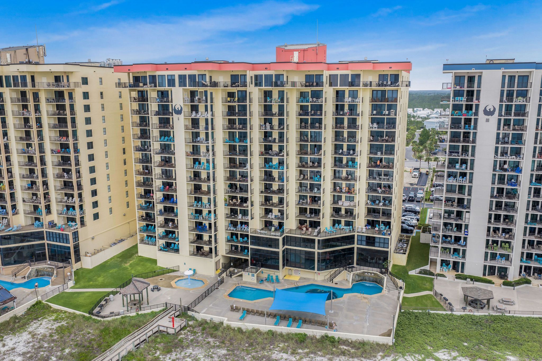 A high-rise hotel with multiple balconies, a swimming pool area, and a landscaped courtyard.