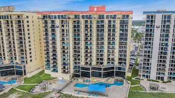 A high-rise hotel with multiple balconies, a swimming pool area, and a landscaped courtyard.