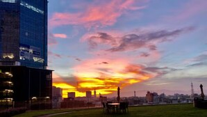 Un paisaje urbano al atardecer con un edificio reflejado en el cielo.