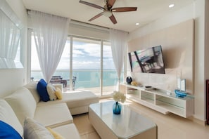 Una sala moderna con sofá, mesa de centro, televisor y un balcón con vistas.