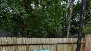 An outdoor deck with wooden flooring, a black wicker sofa, and a blue cushioned bench. - Private Guest House Free Parking 20min to IAH Airport (Houston)