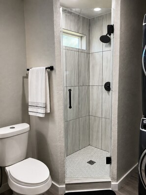 Moderni kylpyhuone, jossa on suihku, wc ja pyyheteline.