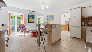 A kitchen with a dining area, a refrigerator, and a window with curtains. - Le Nid Mentonnais - À moins de 100 m de la plage (Menton)