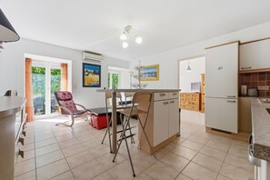Eine Küche mit Essbereich, einem Kühlschrank und einem Fenster mit Vorhängen.