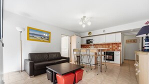 A compact living space with a sofa, dining table, and kitchen area. - Le Nid Mentonnais - À moins de 100 m de la plage (Menton)