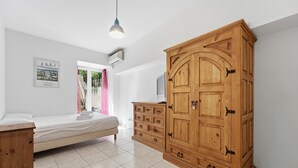 A bedroom with a bed, wooden wardrobe, and a television on a dresser. - Le Nid Mentonnais - À moins de 100 m de la plage (Menton)