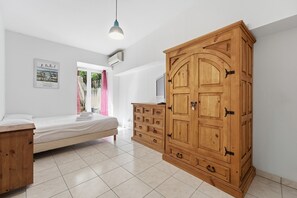 Ein Schlafzimmer mit einem Bett, einem Holzschrank und einem Fernseher auf einer Kommode.