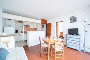 A compact living space with a dining area, kitchenette, and a television. - El Tiburon N°17 - À 250 m de la plage (Argeles-sur-Mer)