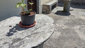 A potted plant on a stone table, a door, a stone bench, and a sign with 'CASA S. GIORGIO' on a building.
