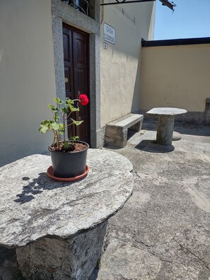 A potted plant on a stone table, a door, a stone bench, and a sign with 'CASA S. GIORGIO' on a building. - Former San Giorgio Parish House between beautiful Lake Como and Lake Lugano (Pellio Intelvi)