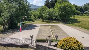 A landscaped area with a flag, lamp posts, and a cross monument.