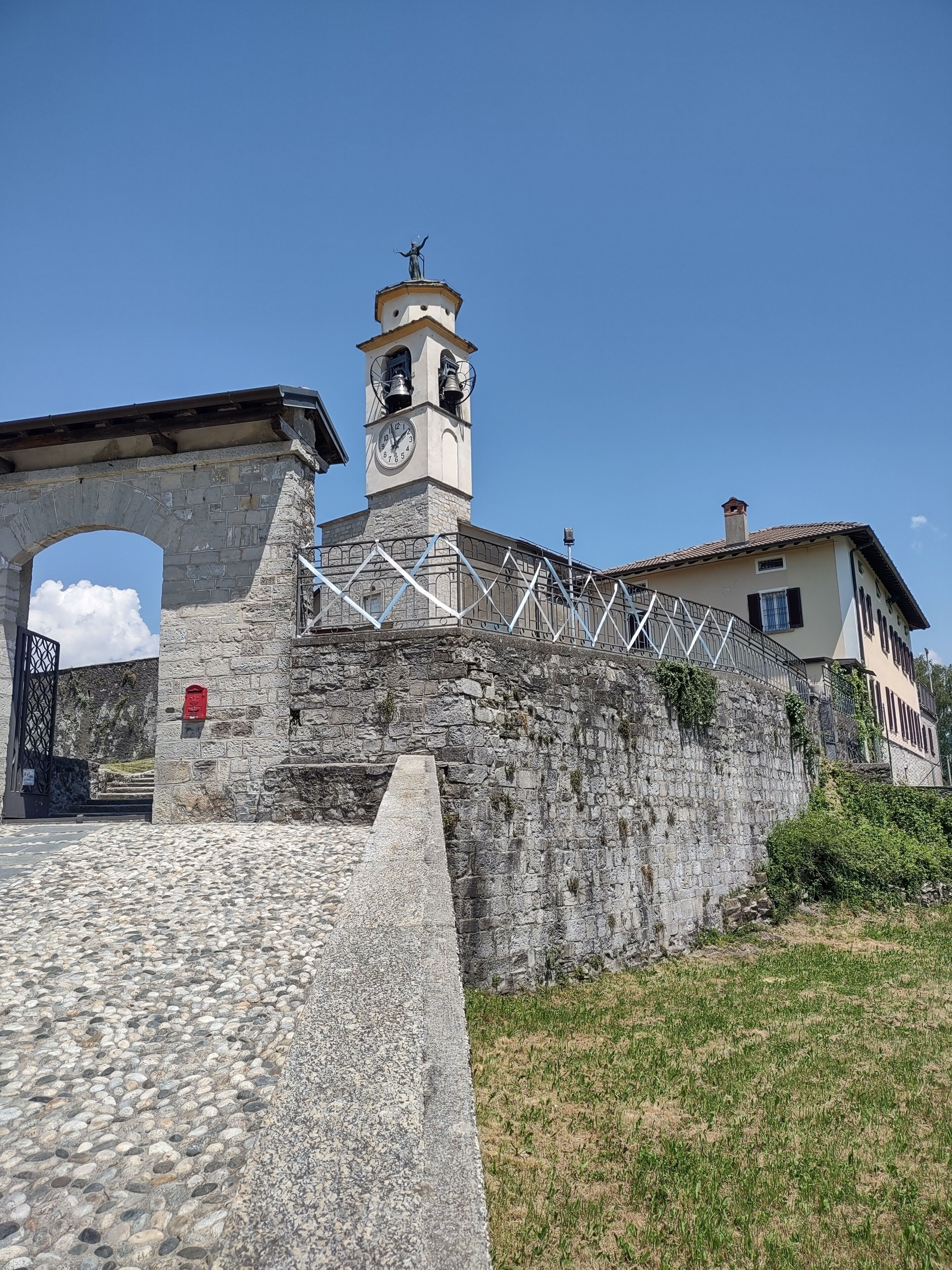 A stone bridge with a clock tower, a gate, and a building with a tiled roof.