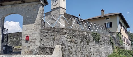 A stone bridge with a clock tower, a gate, and a building with a tiled roof.