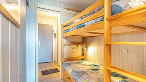 A bunk bed room with a door leading to another room, a bedside table, and a mat on the floor. - Horizon Montagne - À 150 m des Pistes de ski (Villarembert)