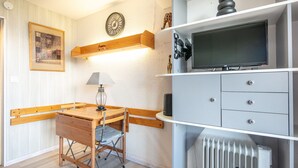 A room with a wooden desk, a lamp, a television on a shelf, and a radiator. - Horizon Montagne - À 150 m des Pistes de ski (Villarembert)