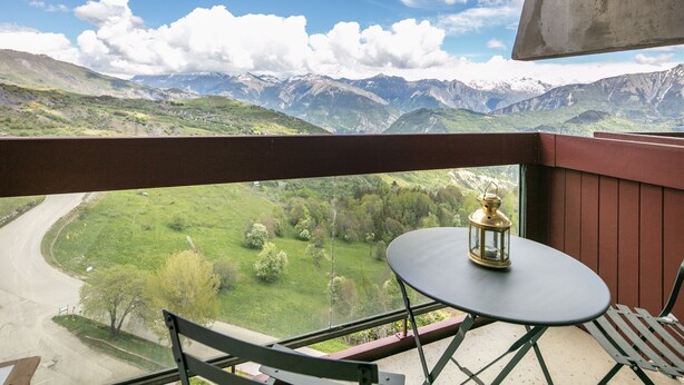 A balcony with a table, chair, and a lantern. - Horizon Montagne - À 150 m des Pistes de ski (Villarembert)
