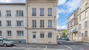 Ein mehrstöckiges Gebäude mit weißer Fassade, zahlreichen Fenstern und Balkonen.