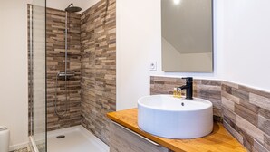 Een moderne badkamer met een douchecabine van glas, een houten wastafelmeubel en een grote spiegel.