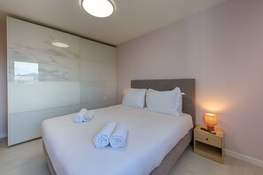 A neatly made bed with rolled white towels, a bedside lamp, and a wooden nightstand. - Le Bel Air du Lac - Proche centre-ville d'Annecy (Annecy)